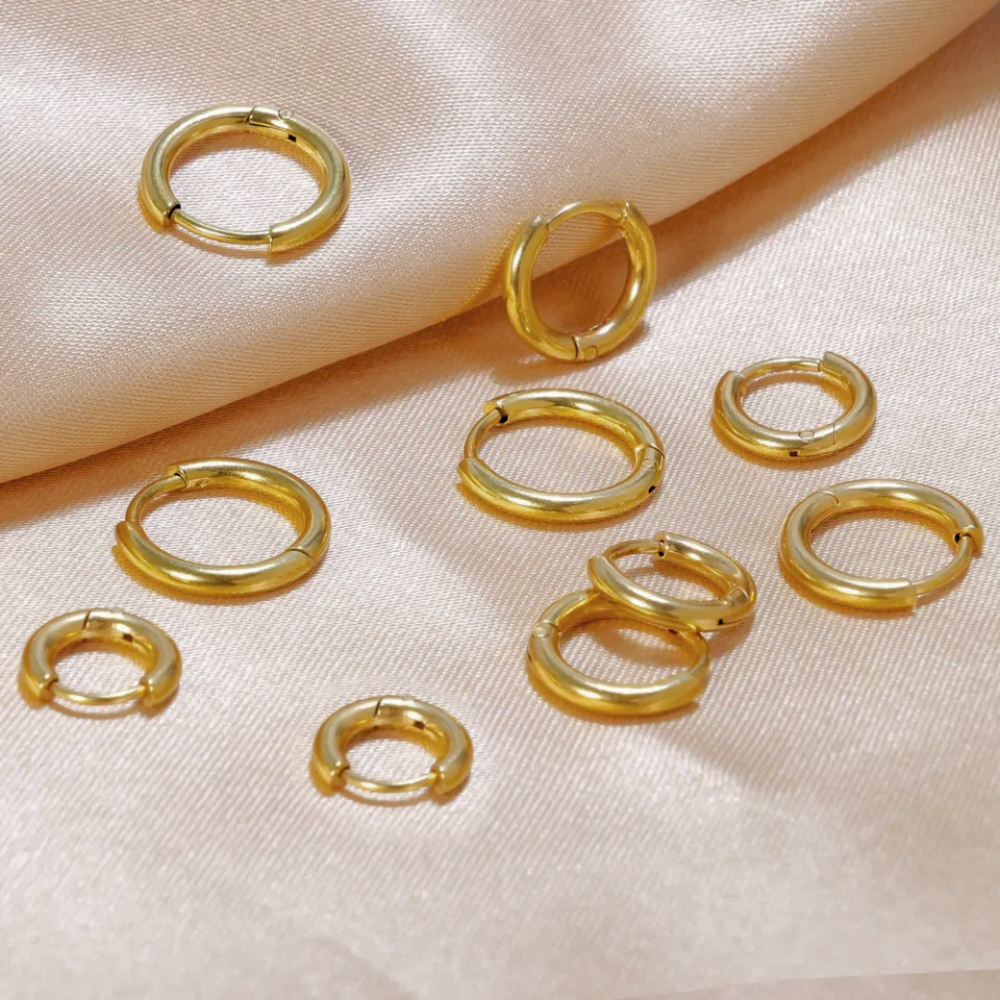 Kolczyki Sienna Huggies wykonane ze stali nierdzewnej pokrytej powłoką PVD w kolorze 14-karatowego złota – wodoodporne i odporne na matowienie kolczyki w kształcie kółek, dostępne w rozmiarach 15 mm, 18 mm i 20 mm.